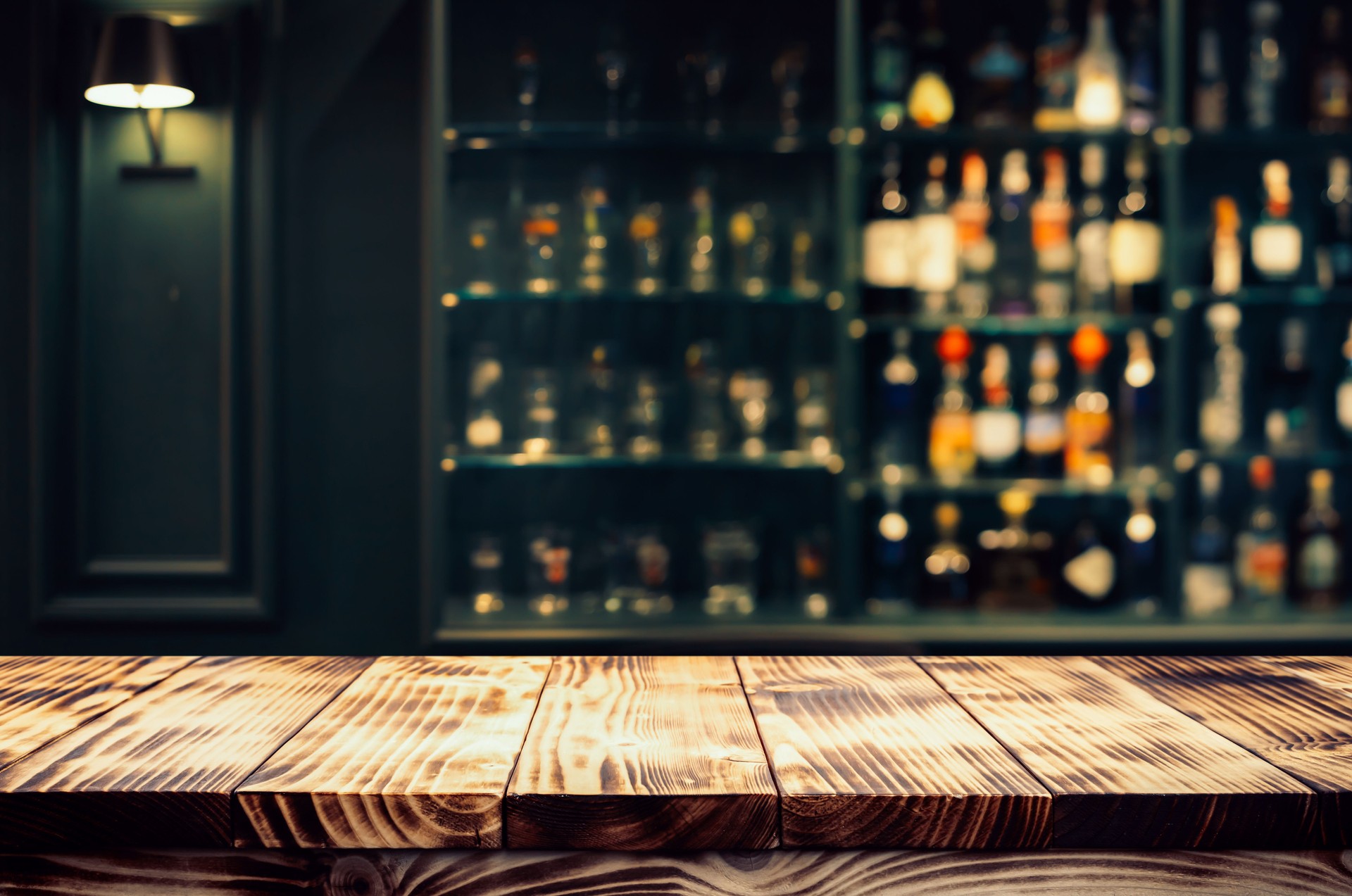 Real photographs material of rustic wooden bar countertop with a warm, ambient background of blurred bottles